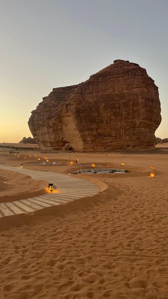 A striking sandstone rock formation in the desert with ambient lighting as the sun sets.